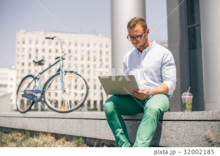 Handsome employee sitting on stairs and typing on Handsome employee sitting on stairs and typing on 32002185
