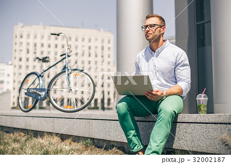 Business man with laptop and sport bike sitting in Business man with laptop and sport bike sitting in 32002187