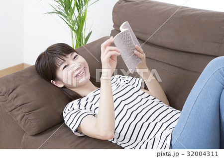 ソファーに寝そべり読書する若い女性 32004311
