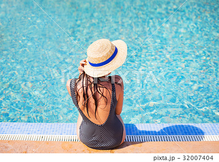 Beautiful girl in a black swimsuit near a blue Beautiful girl in a black swimsuit near a blue 32007404