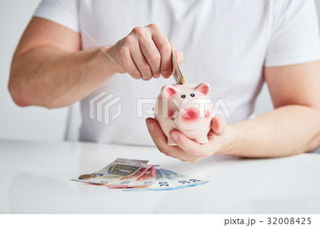 Male hand putting money into piggy bank 32008425