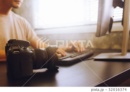 Casual young man working on computer with camera 32016374