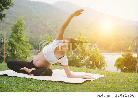 asian pregnant woman practicing yoga on green grass in public park. concept of prenatal exercise, maternity, fitness, healthy lifestyle and relaxation. 32031556