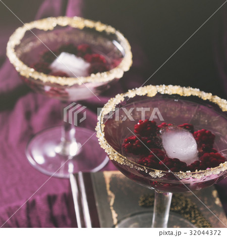 Two alcohol cocktails with berries on purple 32044372