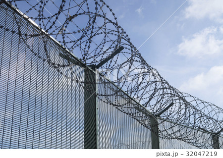 Barbwired fence on a blue sky with clouds Barbwired fence on a blue sky with clouds 32047219