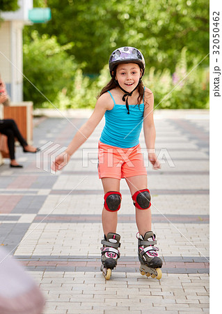 Cute little girl learning to roller skate outdoors 32050462