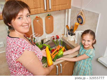 mother and daughter with vegetables in kitchen 32055777