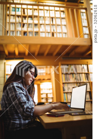 Female student using laptop in library 32062618