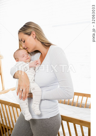 Mother holding and kissing her baby boy Mother holding and kissing her baby boy 32063033