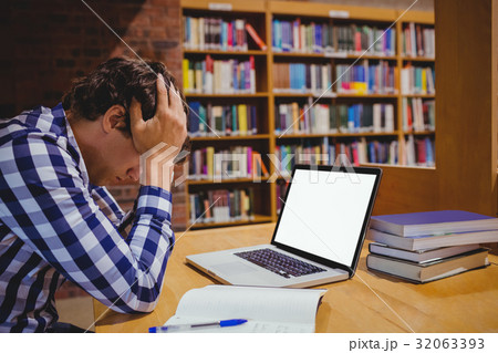 Depressed student sitting in library with laptop Depressed student sitting in library with laptop 32063393