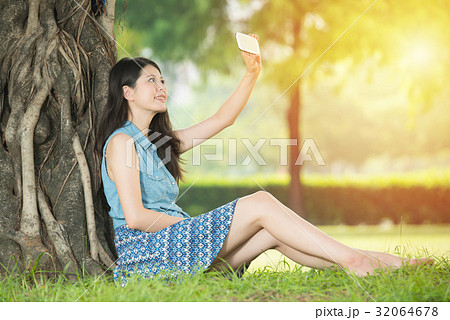 asian woman taking selfie sitting on grass 32064678