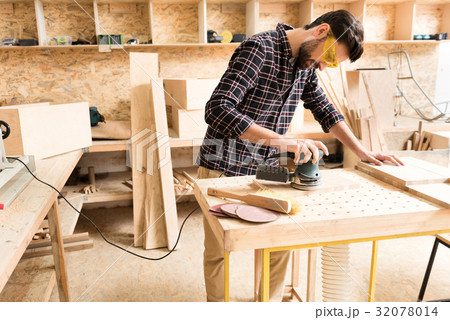 Cheerful woodworker is leaning on table while 32078014