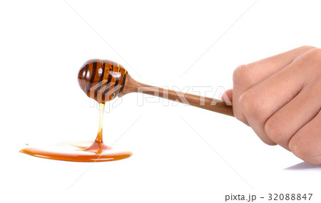 Honey dripping from a wooden honey dipper Honey dripping from a wooden honey dipper 32088847