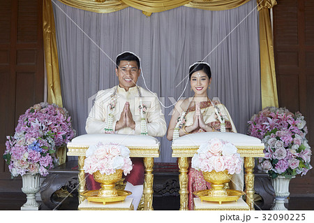 The groom and the bride with the traditional headpiece on their head are smiling 32090225