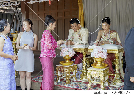 Two women are talking while another woman is pouring water on the couple's hand. 32090228