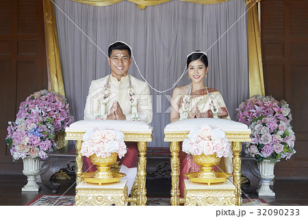A couple with the string headpiece and and garland are smiling in the wedding ceremony. 32090233