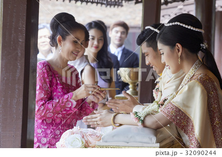 A woman is performing ritual with a groom at the wedding ceremony. A woman is performing ritual with a groom at the wedding ceremony. 32090244