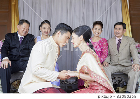 Bride and groom are performing ritual in front of their parents. 32090258
