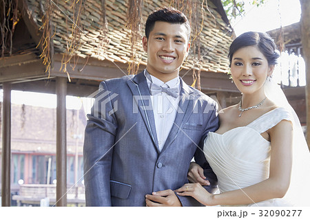 the bride and the groom are standing side by side and smiling  32090277