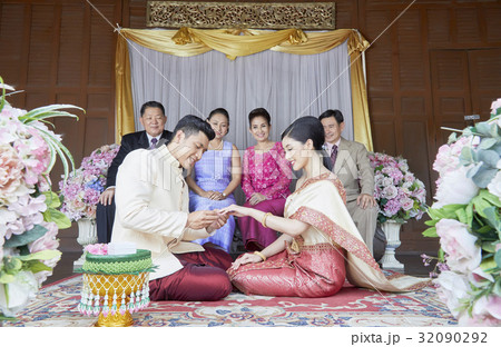 the groom is sitting and wearing a ring into bride's finger the groom is sitting and wearing a ring into bride's finger 32090292