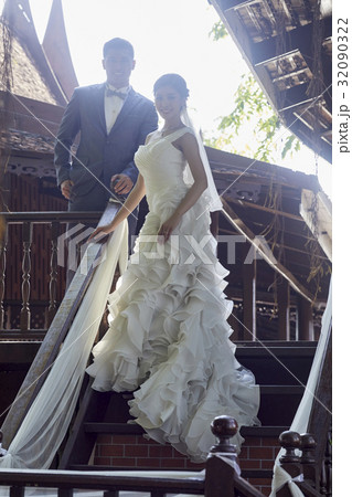 Elegant wedding couple is standing at stairs and smiling Elegant wedding couple is standing at stairs and smiling 32090322