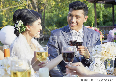 groom and bride are cheering with glasses of wine and smiling 32090337