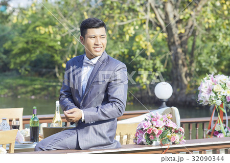 Happy groom in grey suit is sitting at the balcony and looking away Happy groom in grey suit is sitting at the balcony and looking away 32090344
