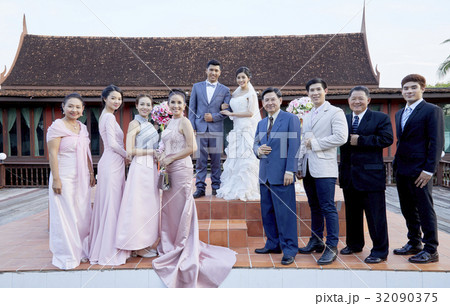 A  photograph of married couple and their family, friends on their wedding with side: men and women  32090375