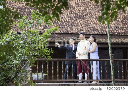 Groom and his parents are standing in the balcony and looking at something 32090379