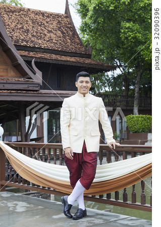 a photo of a happy groom standing and smiling in a balcony 32090396