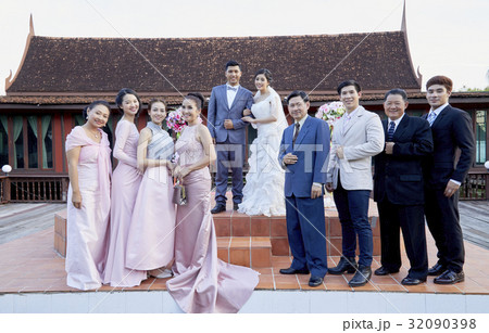 a newlywed couple is posing with their family outdoors a newlywed couple is posing with their family outdoors 32090398