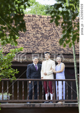 a happy groom is posing with his parents in a balcony a happy groom is posing with his parents in a balcony 32090409