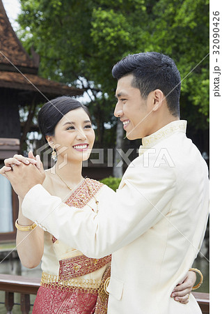 a happy newlywed couple is dancing and smiling outdoors a happy newlywed couple is dancing and smiling outdoors 32090426