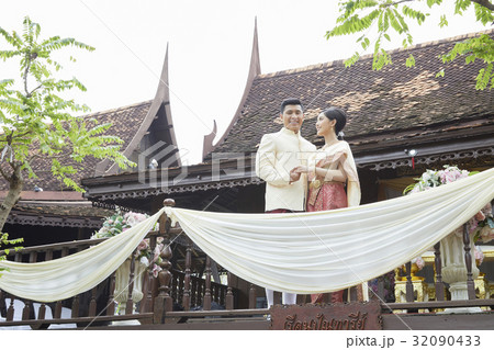 A couple with hand in hand in the wedding is standing in a balcony. 32090433