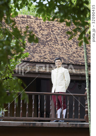 A groom is standing and smiling in the balcony. A groom is standing and smiling in the balcony. 32090435