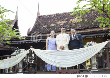 Parents and a groom are standing, posing in the balcony. Parents and a groom are standing, posing in the balcony. 32090450