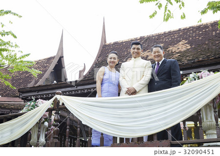 Parents and a groom are standing and smiling in the balcony. 32090451