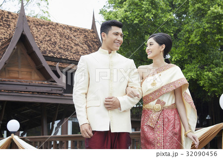 Thai groom and bride are standing, smiling at each other in the garden. 32090456
