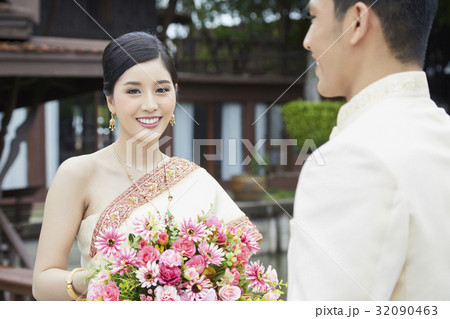 A portrait of a Thai bride smiling next to her groom. 32090463