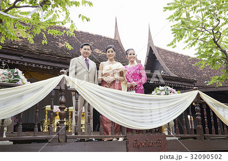 A bride and her parents are standing and smiling in a balcony 32090502
