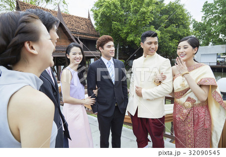 A married couple is smiling happily with guests outside. A married couple is smiling happily with guests outside. 32090545