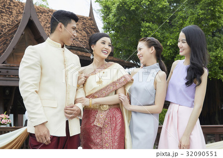 The bride and groom are smiling happily with bridesmaids. 32090551