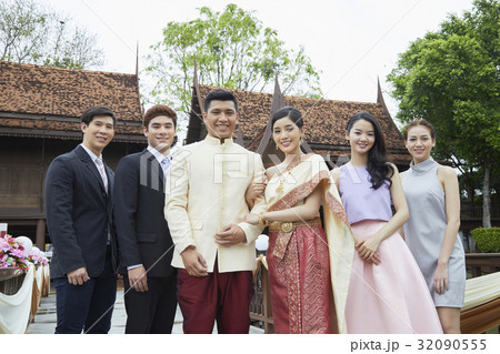 A portrait of a newlywed standing, looking at camera with friends. 32090555