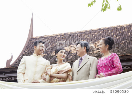 a photo of a groom and bride looking and smiling with their parents. a photo of a groom and bride looking and smiling with their parents. 32090580