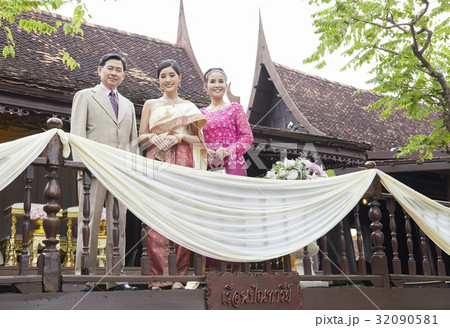 a bride and her parents are smiling and standing side by side on balcony. a bride and her parents are smiling and standing side by side on balcony. 32090581