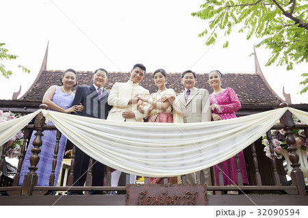 a photo of a groom holding his wife's hand when standing with their parents. 32090594