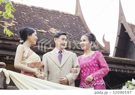 a bride is smiling with her mother while her father is looking at something. a bride is smiling with her mother while her father is looking at something. 32090597