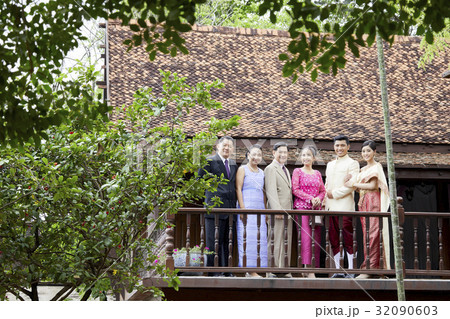 a picture of a groom and bride being taken photo with their family on a balcony. a picture of a groom and bride being taken photo with their family on a balcony. 32090603
