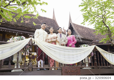 a photo of a groom and bride looking at something beside their parents. a photo of a groom and bride looking at something beside their parents. 32090604