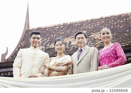 a photo of a couple and parents smiling and standing outside. a photo of a couple and parents smiling and standing outside. 32090608